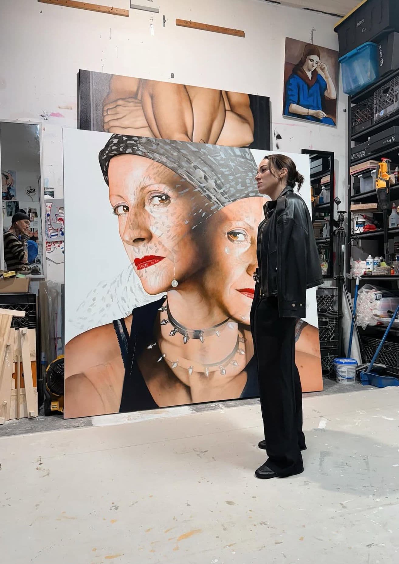 Cordelia, de pie y de perfil, contempla un gran retrato de una mujer de dos rostros en el estudio de la artista.