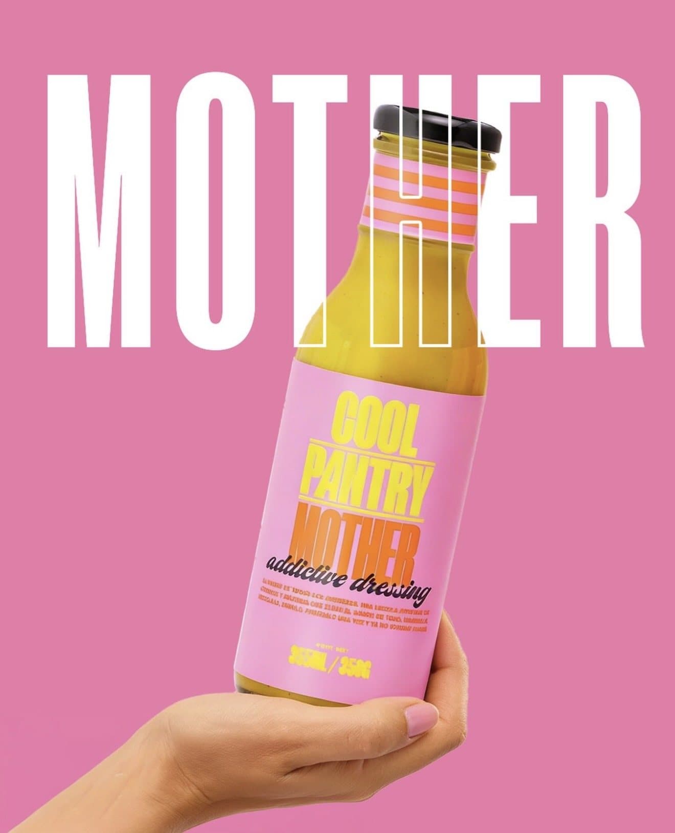 Una mano sostiene una botella del aderezo Mother de Cool Pantry sobre fondo rosa.